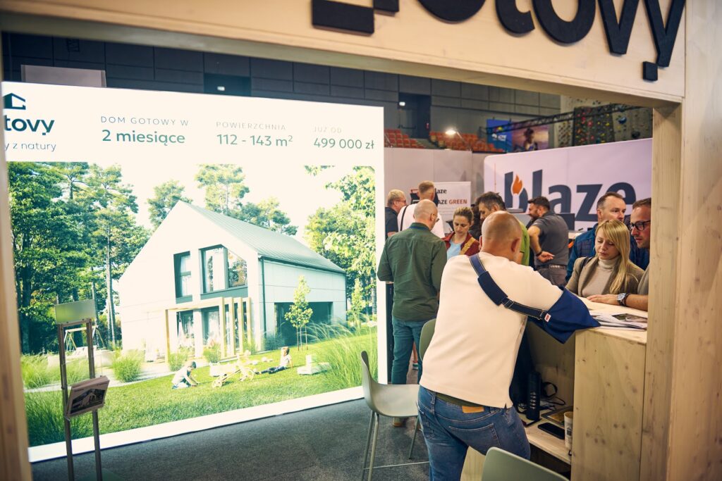 Stoisko z domem na banerze i zwiedzającymi