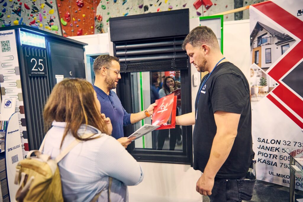Zwiedzający odbiera materiały na stoisku wystawcy